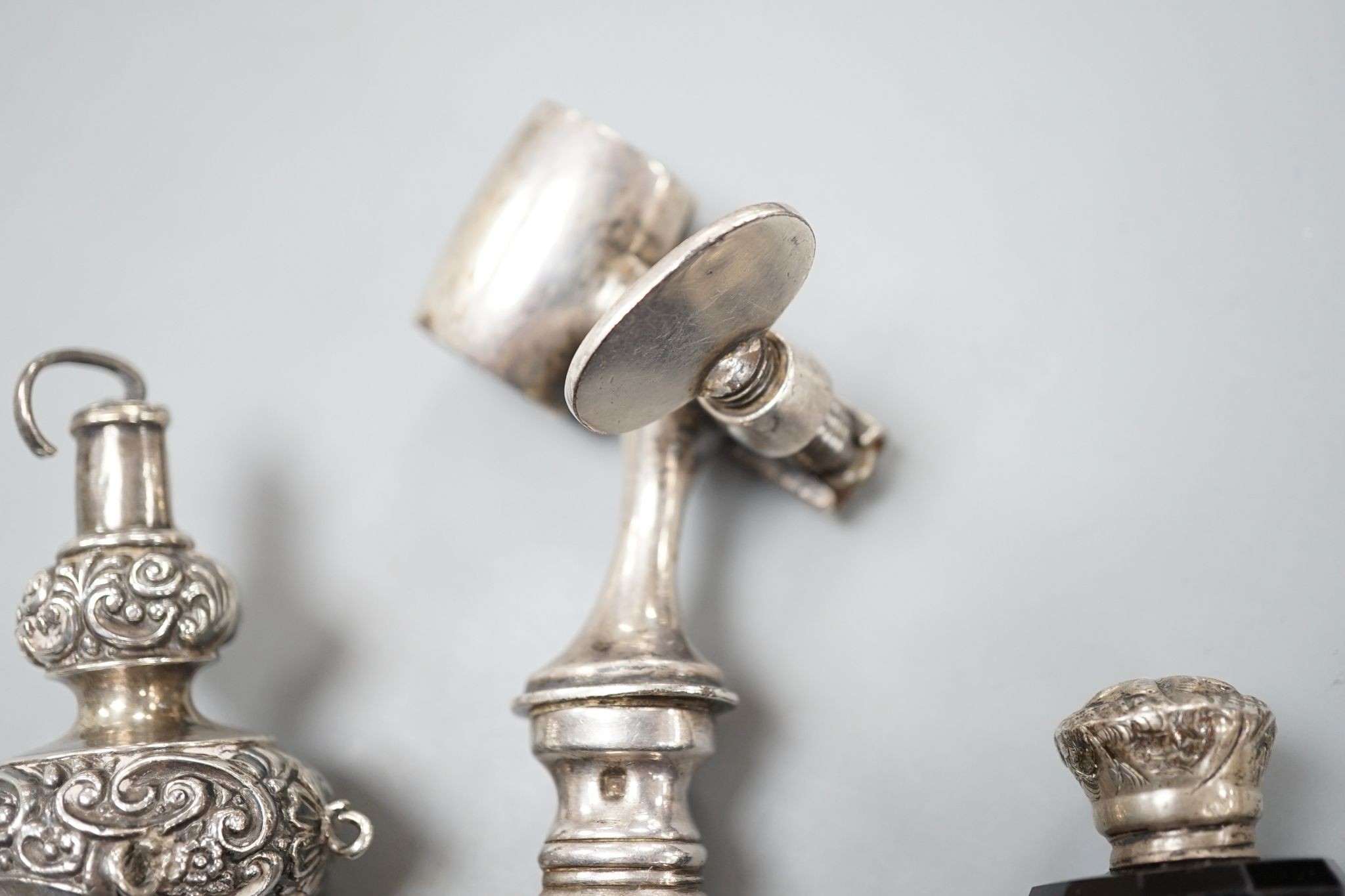 A silver mounted rattle, a white metal mounted double ended ruby glass cent bottle and a silver plated handled roast joint holder.